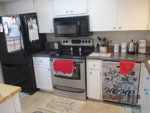 kitchen featuring white cabinetry, light tile patterned floors, and black appliances