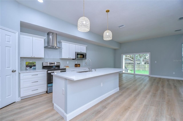 kitchen featuring appliances with stainless steel finishes, sink, white cabinetry, and wall chimney range hood