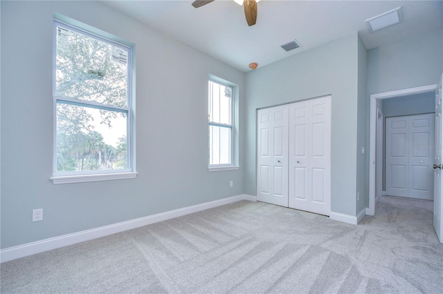 unfurnished bedroom featuring light carpet, ceiling fan, a closet, and multiple windows