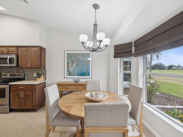 tiled dining area with an inviting chandelier and vaulted ceiling