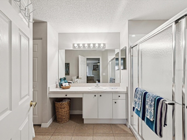 bathroom with a shower with shower door, a textured ceiling, tile patterned floors, and vanity