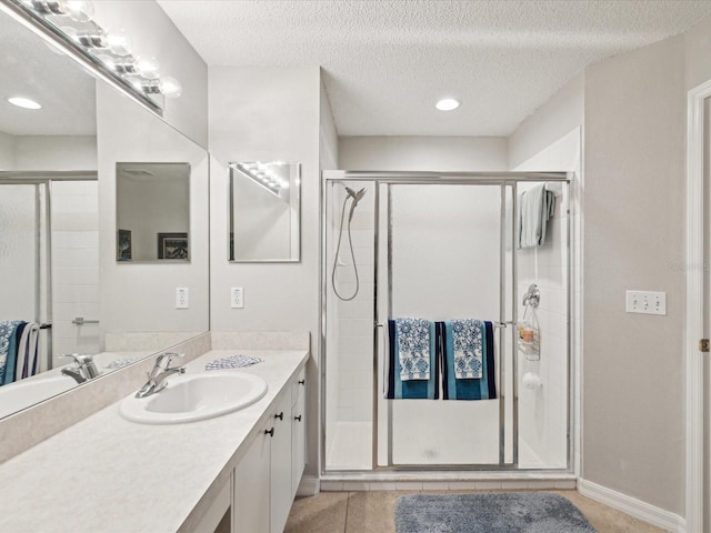 bathroom featuring a textured ceiling, tile patterned flooring, walk in shower, and vanity