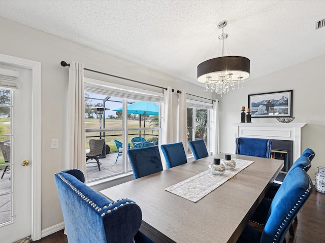 dining room featuring a chandelier, dark wood-type flooring, and a textured ceiling