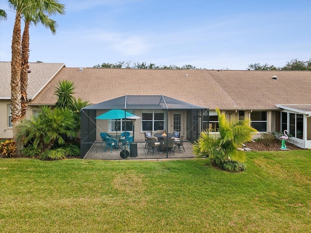 rear view of house with glass enclosure, a patio, and a yard