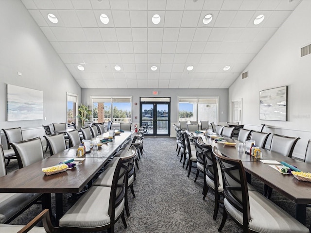 carpeted dining room with french doors and a towering ceiling