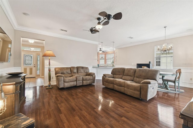 living room featuring a textured ceiling, dark wood-type flooring, ornamental molding, and ceiling fan with notable chandelier