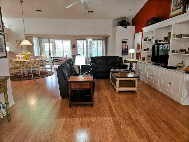 living room featuring ceiling fan, light hardwood / wood-style flooring, and vaulted ceiling