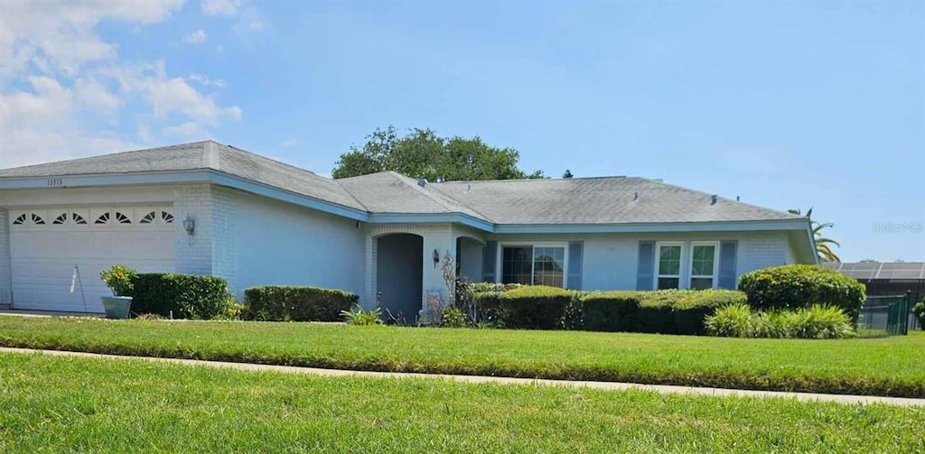 ranch-style house with a garage and a front lawn