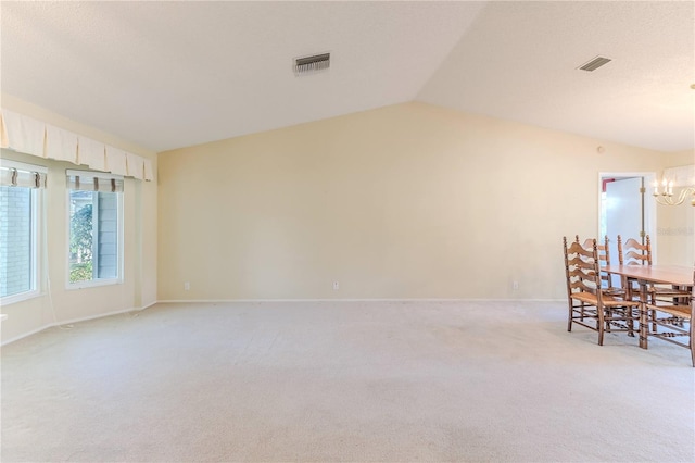 carpeted dining room featuring lofted ceiling and an inviting chandelier