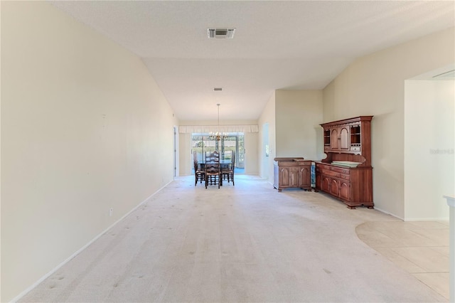 hallway with a chandelier, lofted ceiling, and light colored carpet