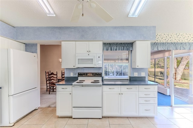 kitchen with light tile patterned floors, white appliances, white cabinets, and a textured ceiling