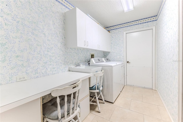 washroom featuring a textured ceiling, light tile patterned flooring, washing machine and clothes dryer, and cabinets