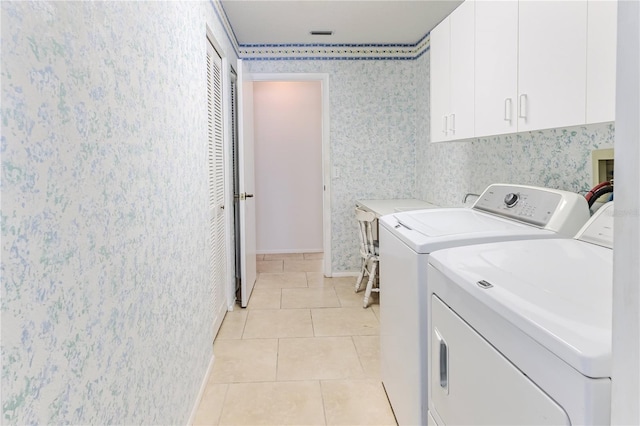 clothes washing area featuring cabinets, separate washer and dryer, and light tile patterned floors