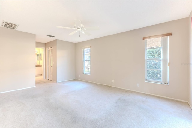 carpeted spare room featuring ceiling fan and a wealth of natural light