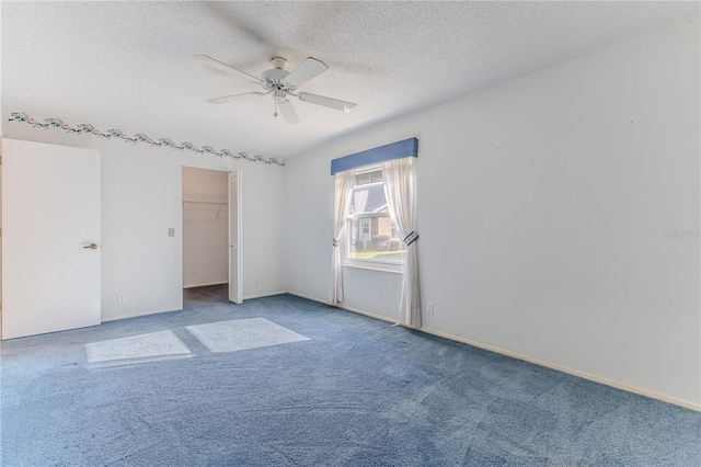 unfurnished bedroom with ceiling fan, carpet flooring, a textured ceiling, a walk in closet, and a closet