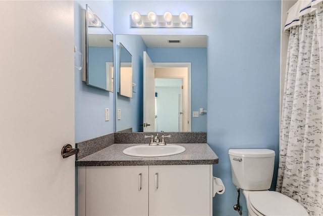 bathroom with curtained shower, toilet, and vanity