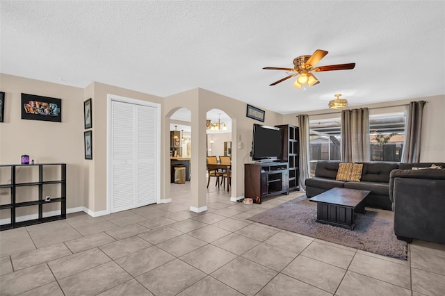 living room with ceiling fan with notable chandelier, a textured ceiling, and light tile patterned floors