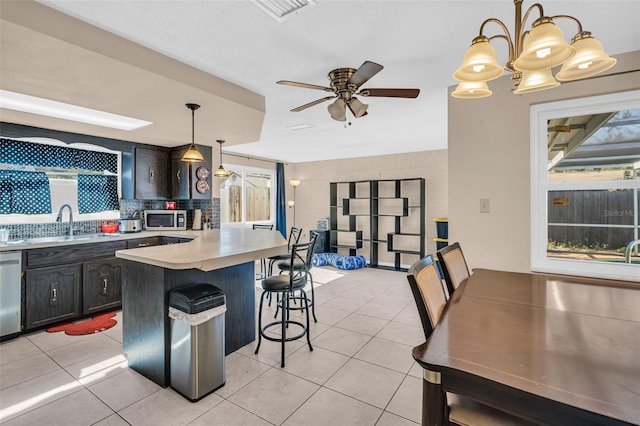 kitchen featuring stainless steel appliances, a kitchen bar, light tile patterned floors, and hanging light fixtures