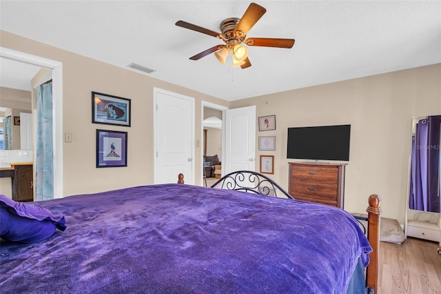 bedroom featuring ensuite bath, a textured ceiling, ceiling fan, and light hardwood / wood-style flooring