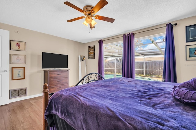 bedroom featuring ceiling fan, light hardwood / wood-style floors, and a textured ceiling