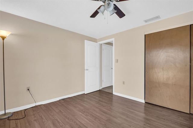 unfurnished bedroom with a closet, ceiling fan, and dark wood-type flooring