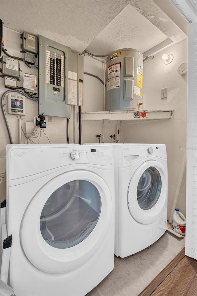 washroom with hardwood / wood-style floors, electric panel, water heater, a textured ceiling, and washer and clothes dryer