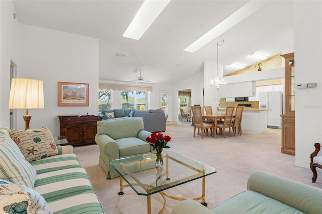 living room with light carpet, a skylight, ceiling fan with notable chandelier, and high vaulted ceiling