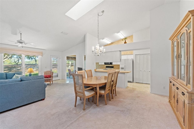 carpeted dining area featuring ceiling fan with notable chandelier, high vaulted ceiling, and a skylight