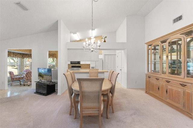 carpeted dining area featuring high vaulted ceiling and a notable chandelier