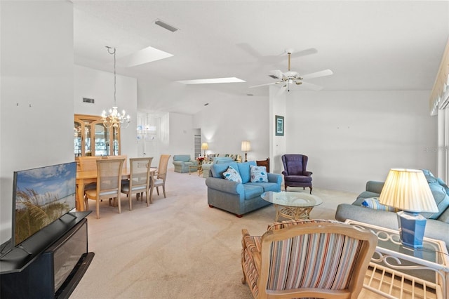 carpeted living room featuring vaulted ceiling with skylight and ceiling fan with notable chandelier