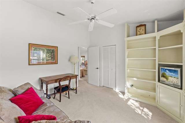 interior space featuring light carpet, ceiling fan, and a high ceiling