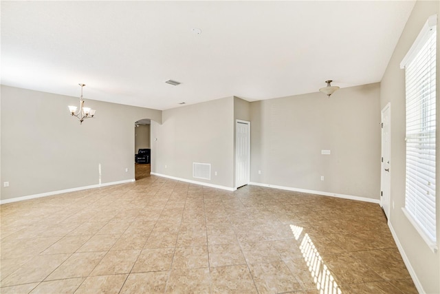 spare room featuring light tile patterned floors and an inviting chandelier