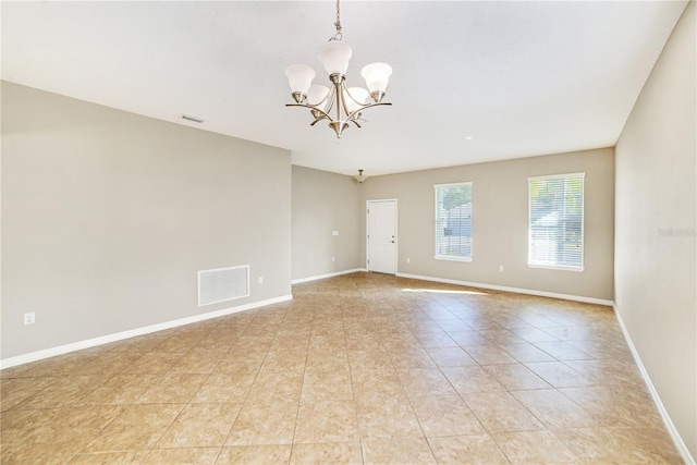 tiled spare room featuring a chandelier