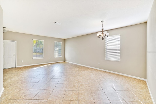 tiled empty room featuring a chandelier