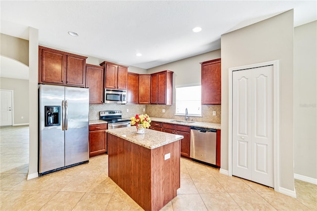 kitchen with light tile patterned floors, stainless steel appliances, light stone countertops, a kitchen island, and sink