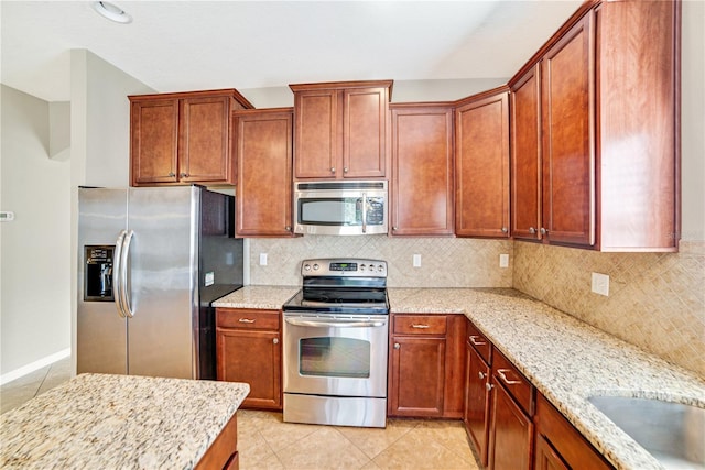 kitchen with tasteful backsplash, light stone countertops, light tile patterned flooring, and stainless steel appliances