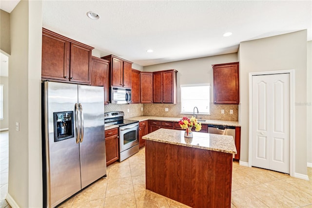 kitchen with tasteful backsplash, a kitchen island, appliances with stainless steel finishes, light tile patterned floors, and light stone counters