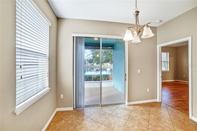 unfurnished dining area with plenty of natural light, an inviting chandelier, and tile patterned flooring