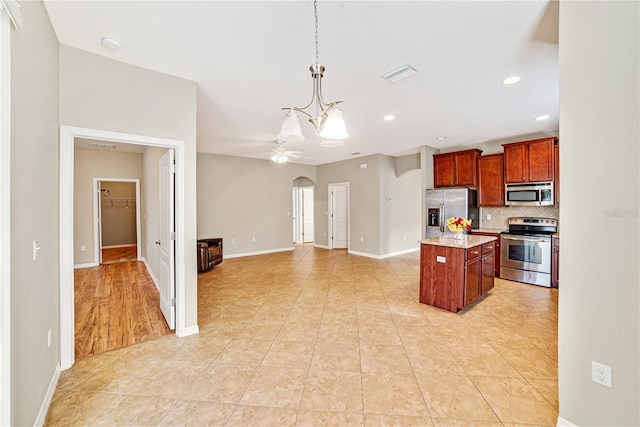 kitchen with backsplash, a kitchen island, hanging light fixtures, stainless steel appliances, and ceiling fan with notable chandelier