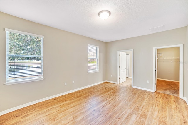 unfurnished bedroom featuring light wood-type flooring, a closet, and a walk in closet