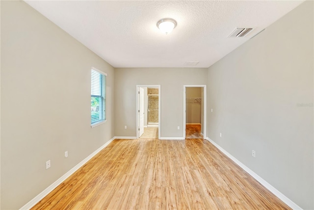 unfurnished room featuring a textured ceiling and light wood-type flooring