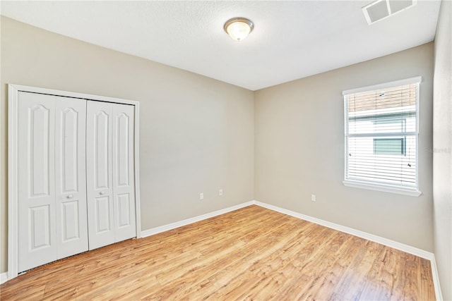 unfurnished bedroom featuring a closet and light wood-type flooring