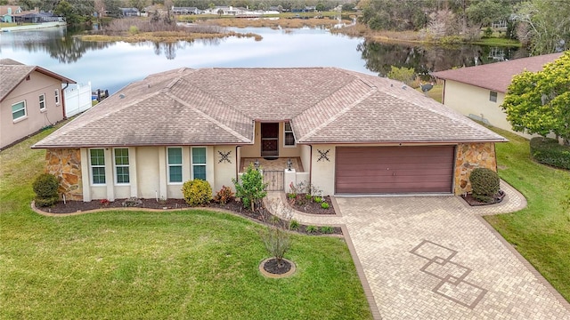 single story home featuring a garage, a front yard, and a water view