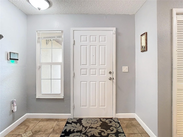 entryway with light tile patterned floors and a textured ceiling