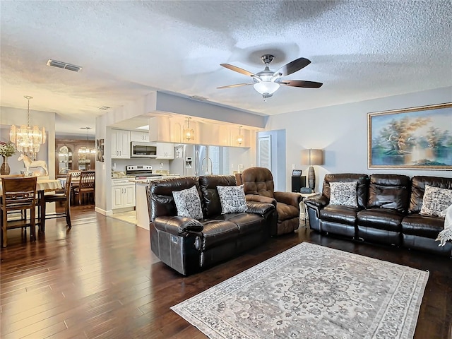 living room featuring ceiling fan with notable chandelier, a textured ceiling, and dark hardwood / wood-style floors