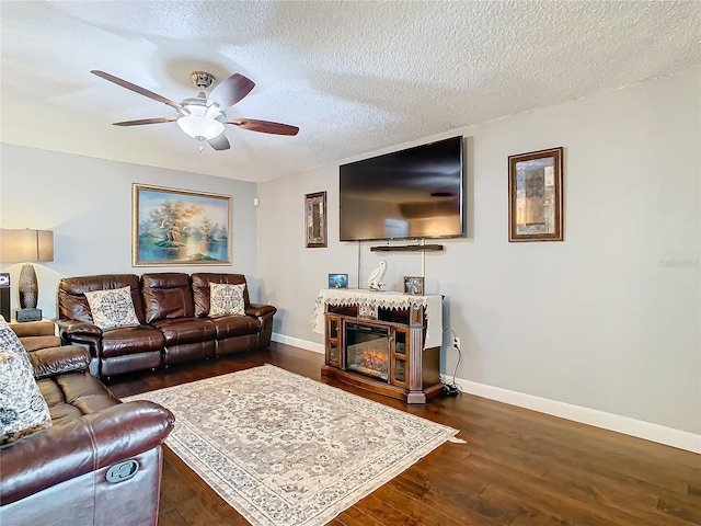 living room with ceiling fan, dark wood-type flooring, and a textured ceiling