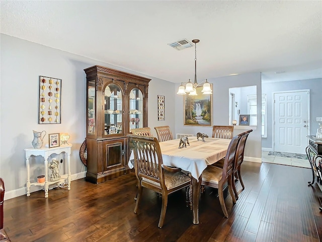 dining space with dark wood-type flooring and a notable chandelier