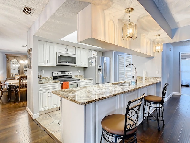 kitchen featuring light stone counters, kitchen peninsula, white cabinets, and stainless steel appliances