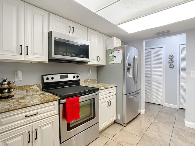 kitchen with light stone countertops, white cabinetry, light tile patterned floors, and stainless steel appliances