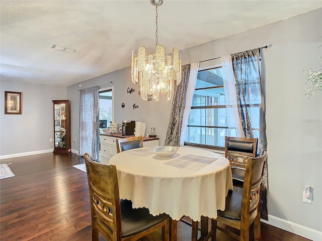 dining space featuring dark hardwood / wood-style flooring, a textured ceiling, and a notable chandelier